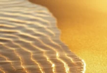 A simple iPhone wallpaper of a smooth beach with soft, flowing waves and a golden horizon.