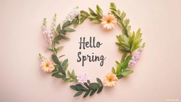 Flat lay of spring flowers and leaves arranged in a circular wreath with Hello Spring in the center in a soft pastel cursive font.