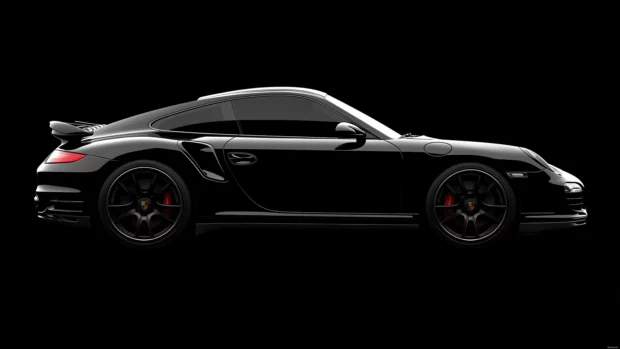 8K Car Wallpaper with a black Porsche 911 Turbo S with its curves subtly outlined by soft edge lighting, set against a matte black background.