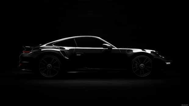 A black Porsche 911 Turbo S with its curves subtly outlined by soft edge lighting, set against a matte black background.