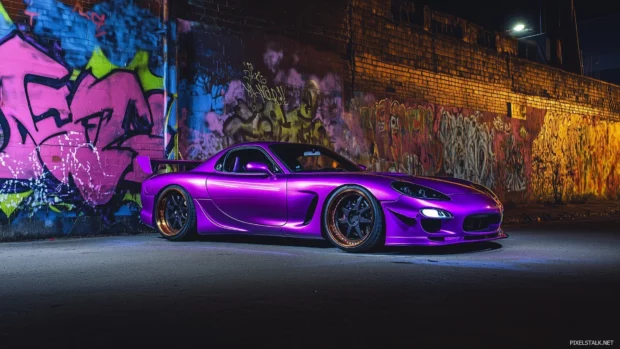 A neon purple Mazda RX 7, parked in front of a graffiti covered wall at night, with a mixture of shadows and glowing lights from nearby signs illuminating its body.