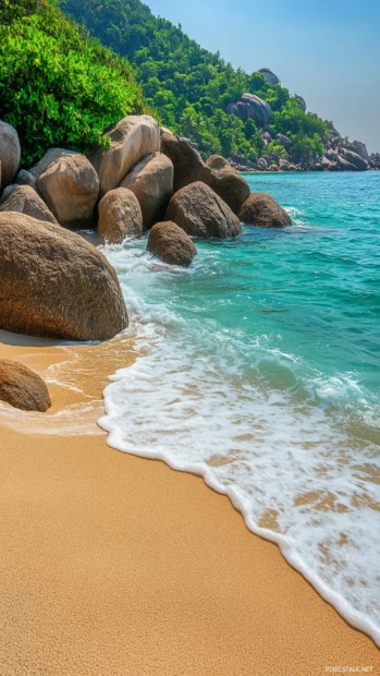 A picturesque beach iPhone Wallpaper with turquoise waves washing up on a soft sandy shore, large boulders.