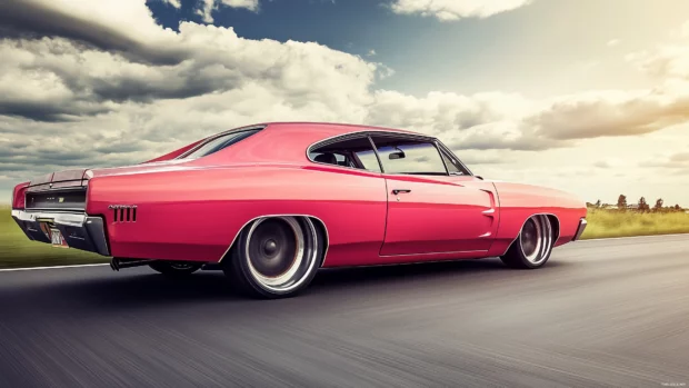 A pink muscle car in motion, speeding down a road.