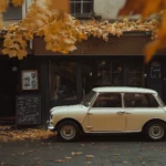 A retro Mini Cooper parked in front of a quaint European café.