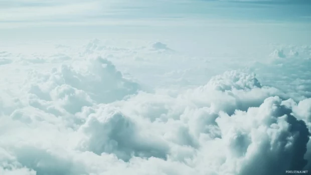 A serene blue sky with soft, white fluffy clouds.