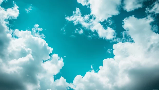 A serene blue sky with soft, white fluffy clouds drifting slowly across the horizon.