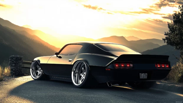 A sleek black Camaro parked on a mountain road with a breathtaking sunset in the background.