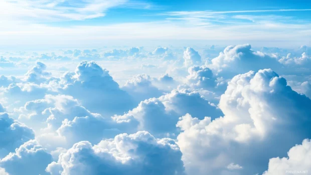 A vast sky filled with soft, billowing blue clouds drifting peacefully, creating a calming and serene atmosphere.