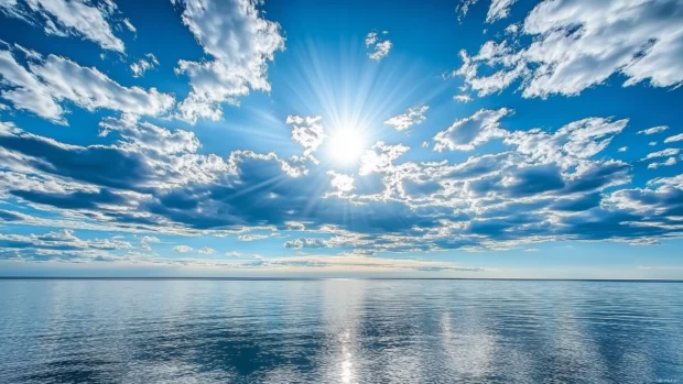 Bright blue clouds gently illuminated by the midday sun, floating over a calm ocean.