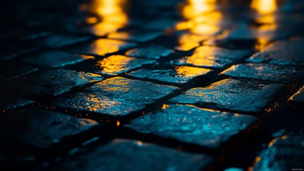 Rain pouring over a quiet cobblestone street at night.