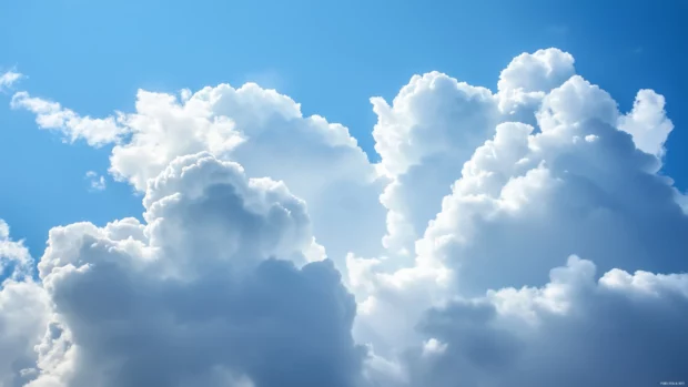 Soft, fluffy blue clouds casting light shadows over a pristine horizon, with gentle sunlight breaking through.