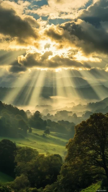 Sunbeams piercing through thick clouds, casting a beautiful display of light and shadow over a lush green landscape below.