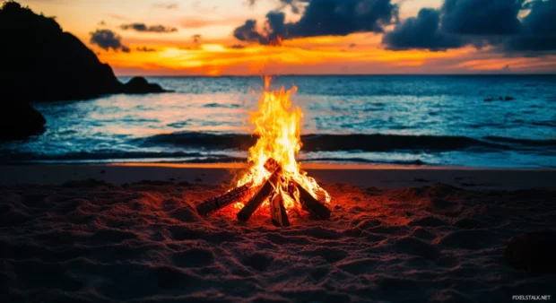 A HD beach scene with bonfire burning brightly as the sun rises.