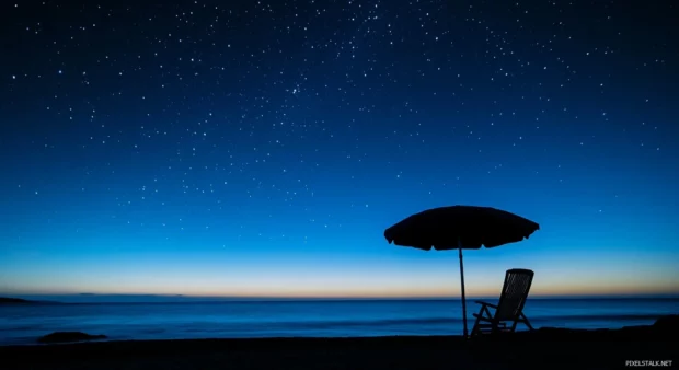 A beach chair and umbrella silhouetted against a starry sky with beachy vibe.