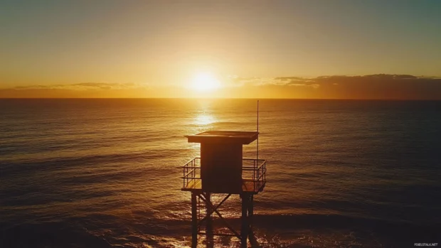 A beachside lifeguard tower silhouetted against a stunning sunrise.