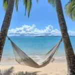 A beachy wallpaper with a hammock tied between two palm trees .