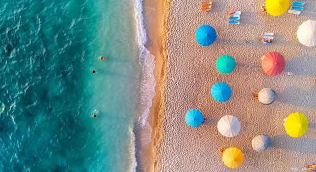 A bird's eye view of a beach at sunrise with colorful umbrellas for desktop background.