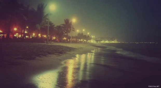 A photograph of a beach at dark night.