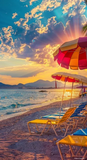 A preppy beachy background at sunset with colorful beach umbrellas and elegant beach chairs.