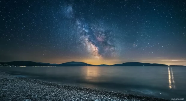 A starry sky above a beach, with the Milky Way galaxy visible in the distance.