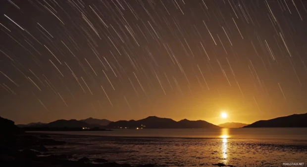 A time lapse photo of the stars moving across the night sky above a beach.