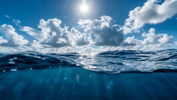 A bright sunny day over a clear blue ocean wallpaper 4K with gentle waves.