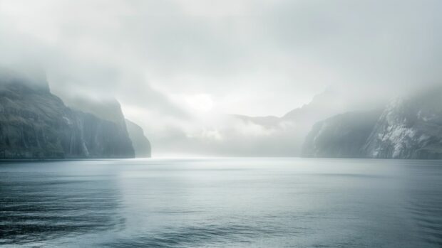 A misty morning over a calm ocean desktop wallpaper with soft light filtering through the fog.
