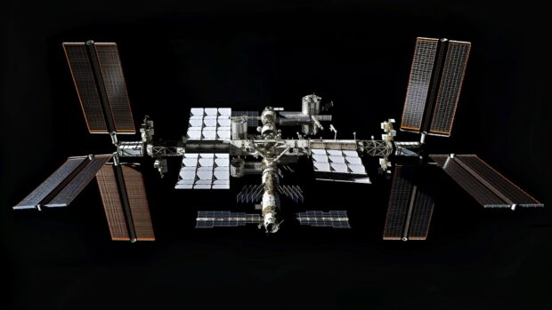 A panoramic view of the International Space Station with all its modules and solar arrays fully extended, floating in orbit HD wallpaper for desktop.