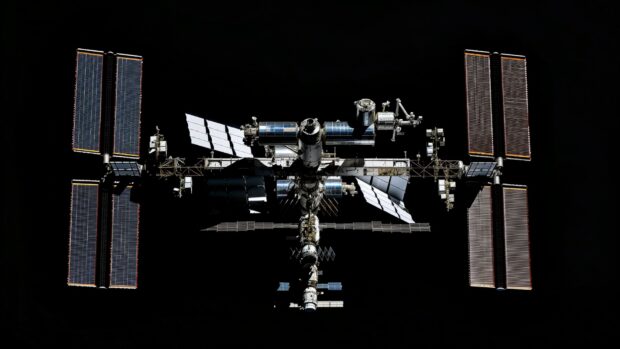 A panoramic view of the International Space Station with all its modules and solar arrays fully extended, floating in orbit HD wallpaper free download.