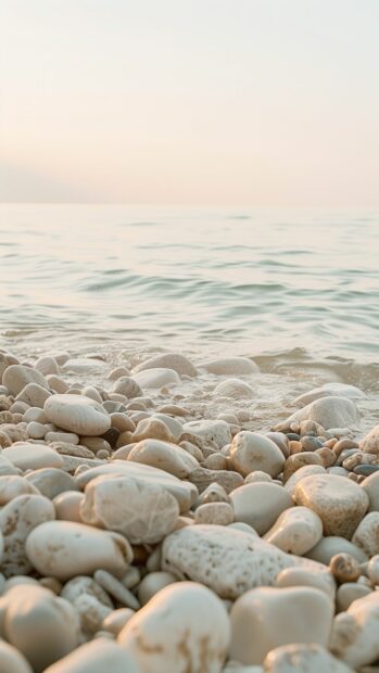 A quiet Beach iPhone wallpaper with smooth pebbles and a misty, pastel colored sky.