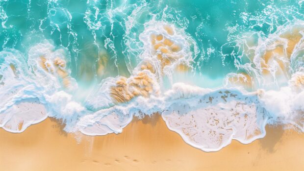 Aerial view of turquoise ocean waves rolling towards a sandy beach background.