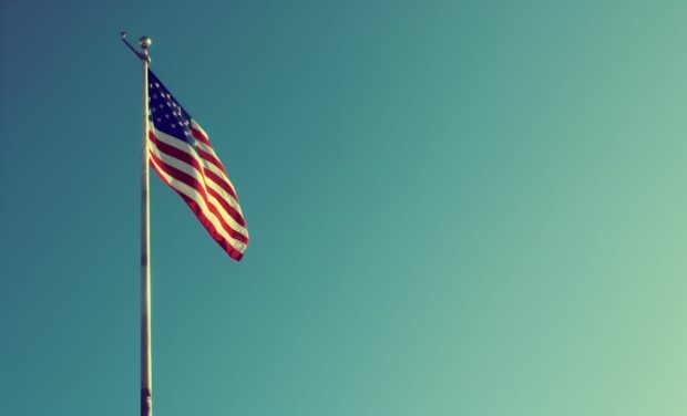 American flag on a flagpole against a clear blue sky.