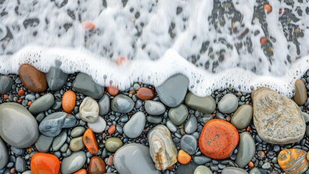 Beach 4K Wallpaper with smooth, colorful pebbles and gentle waves lapping the shore.