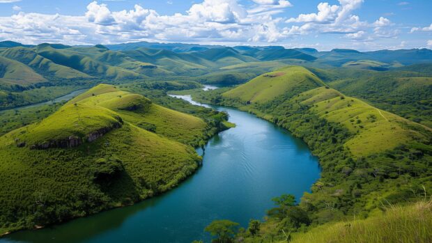 Bing Daily background 4K with Serene river flowing through a verdant valley, vibrant green hills, clear blue sky.