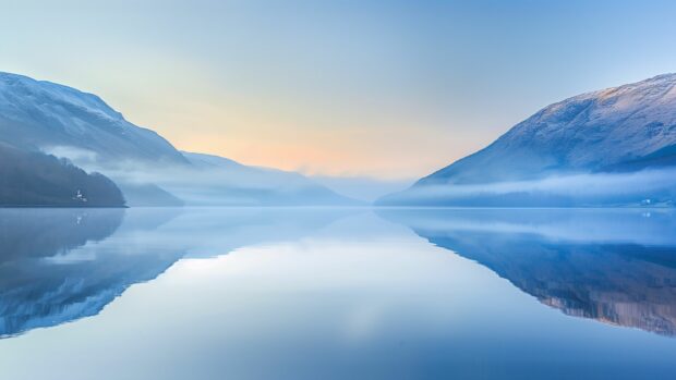 Calm Desktop Wallpaper 4K features a tranquil lake surrounded by mountains at dawn with mist rising from the water.