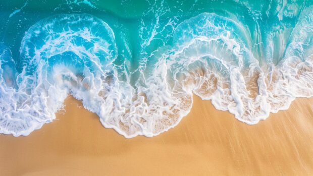 Desktop background with Aerial view of turquoise ocean waves rolling towards a sandy beach.