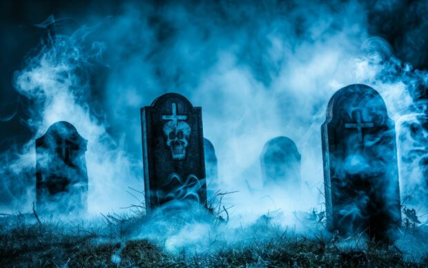 Eerie Halloween graveyard Background with fog swirling around tombstones.