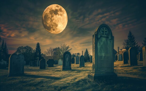 Halloween full moon casting shadows over a creepy graveyard.