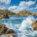 Ocean Desktop Wallpaper with a rocky coastline with waves splashing against the rocks.