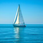 Ocean HD background with a quiet ocean with a lone sailboat in the distance.