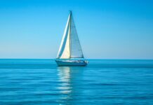 Ocean HD background with a quiet ocean with a lone sailboat in the distance.