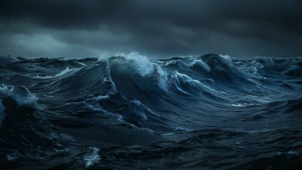 Waves crashing in a tumultuous ocean storm under dark clouds, desktop background.