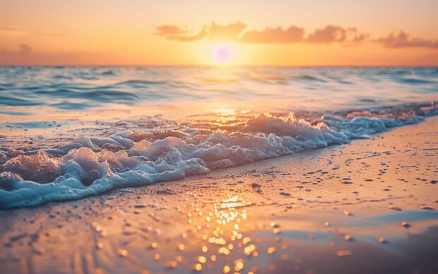 Waves gently lapping the shore during a golden hour ocean sunset, HD Beach Sunset Desktop Background.