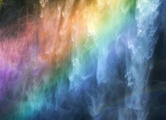 4K HD Wallpaper with a rainbow over a waterfall, with mist and sunlight creating a magical atmosphere.