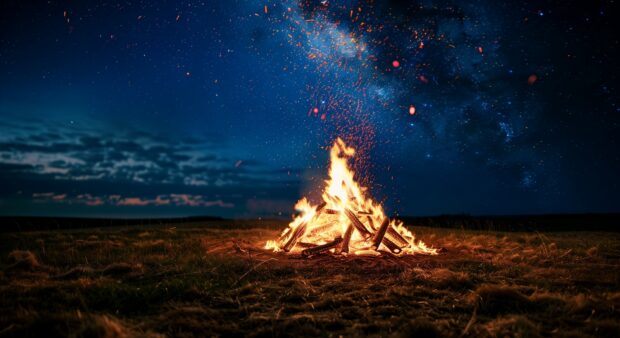 A roaring Campfire under a starry night sky, with sparks flying into the air.