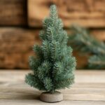 A small, tastefully decorated Christmas tree on a wooden floor.