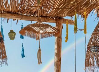 A stylish preppy beach mobile wallpaper with a rainbow over the ocean.