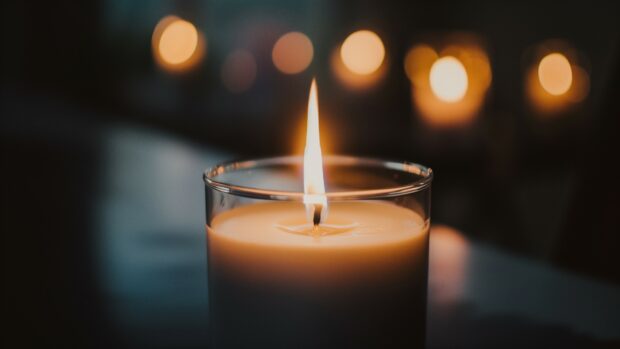 Fire 4K wallpaper with a close up of a candle flame flickering in the dark, casting a warm, gentle light.