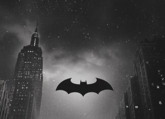 The Bat Signal shining in the night sky over a silhouette of Gotham City.