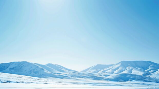 Winter wonderland desktop wallpaper with snow covered mountains and a clear blue sky.